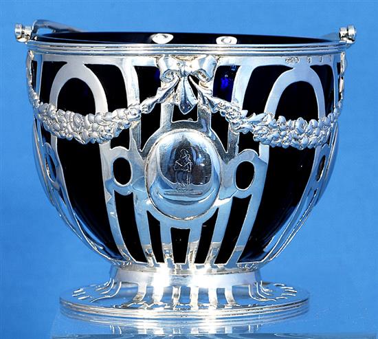 An Edwardian pierced silver sugar basket and blue glass liner, Height to handle 6”/155mm Dia 104mm Weight Silver only: 5.1oz/145grms